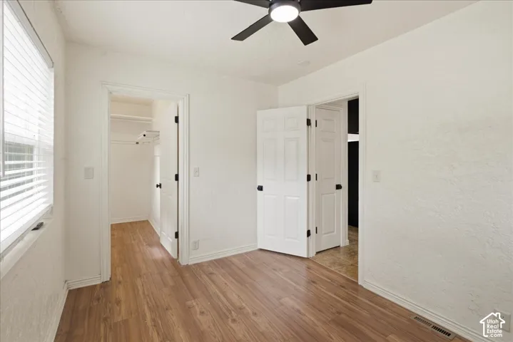 Bedroom featuring wood-finish flooring, white walls, and a ceiling fan with integrated lighting