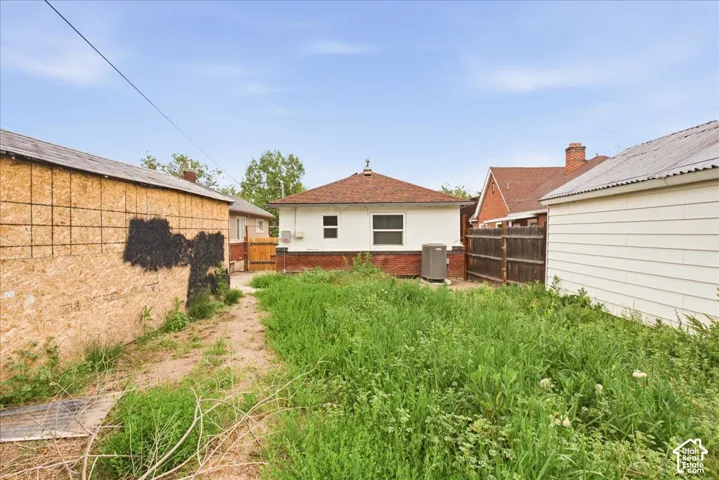 Rear exterior of the property featuring a brick foundation and a brown shingled roof