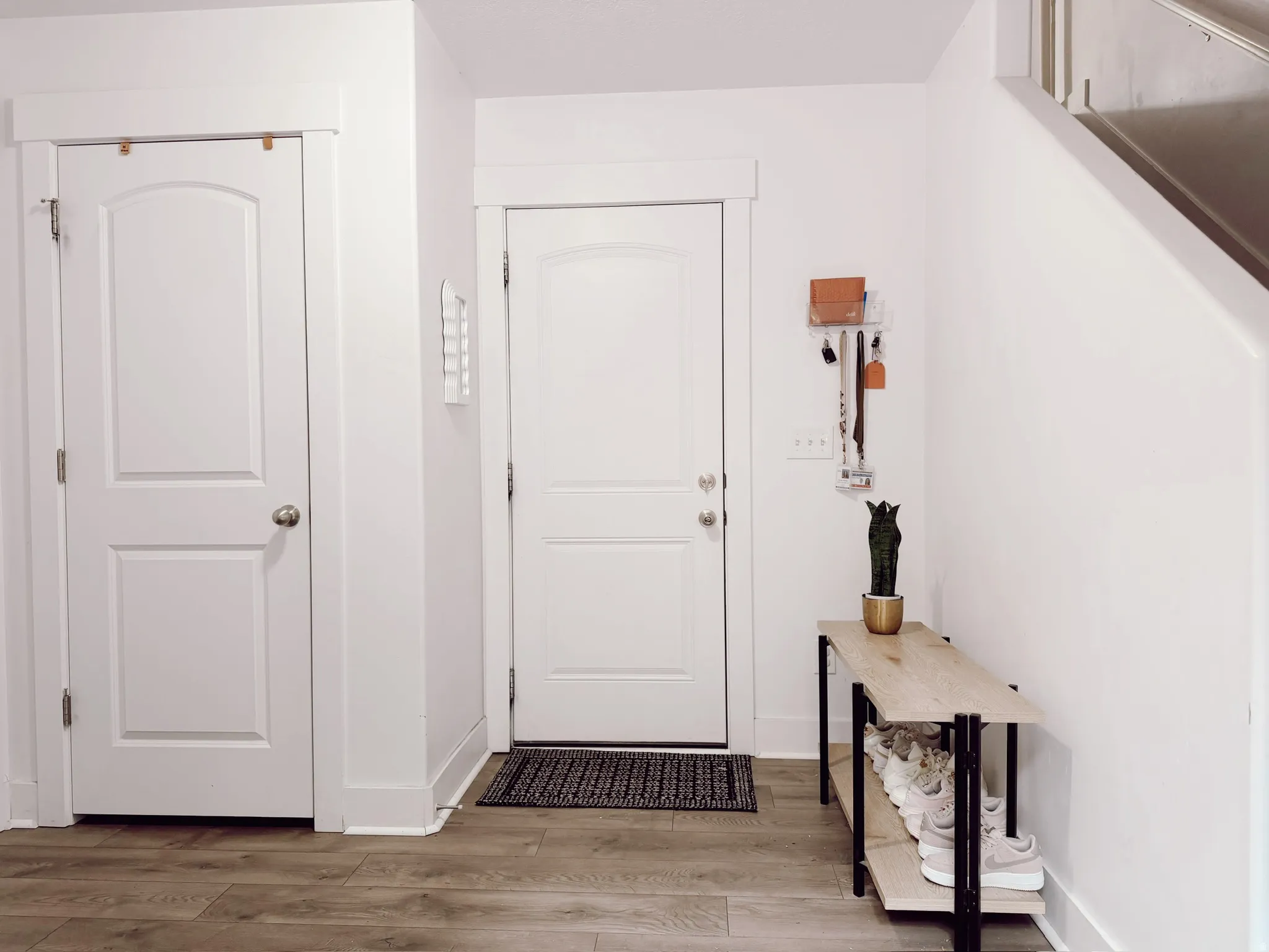 Garage doorway featuring wood-finish flooring, white paneled doors, and clean white baseboards