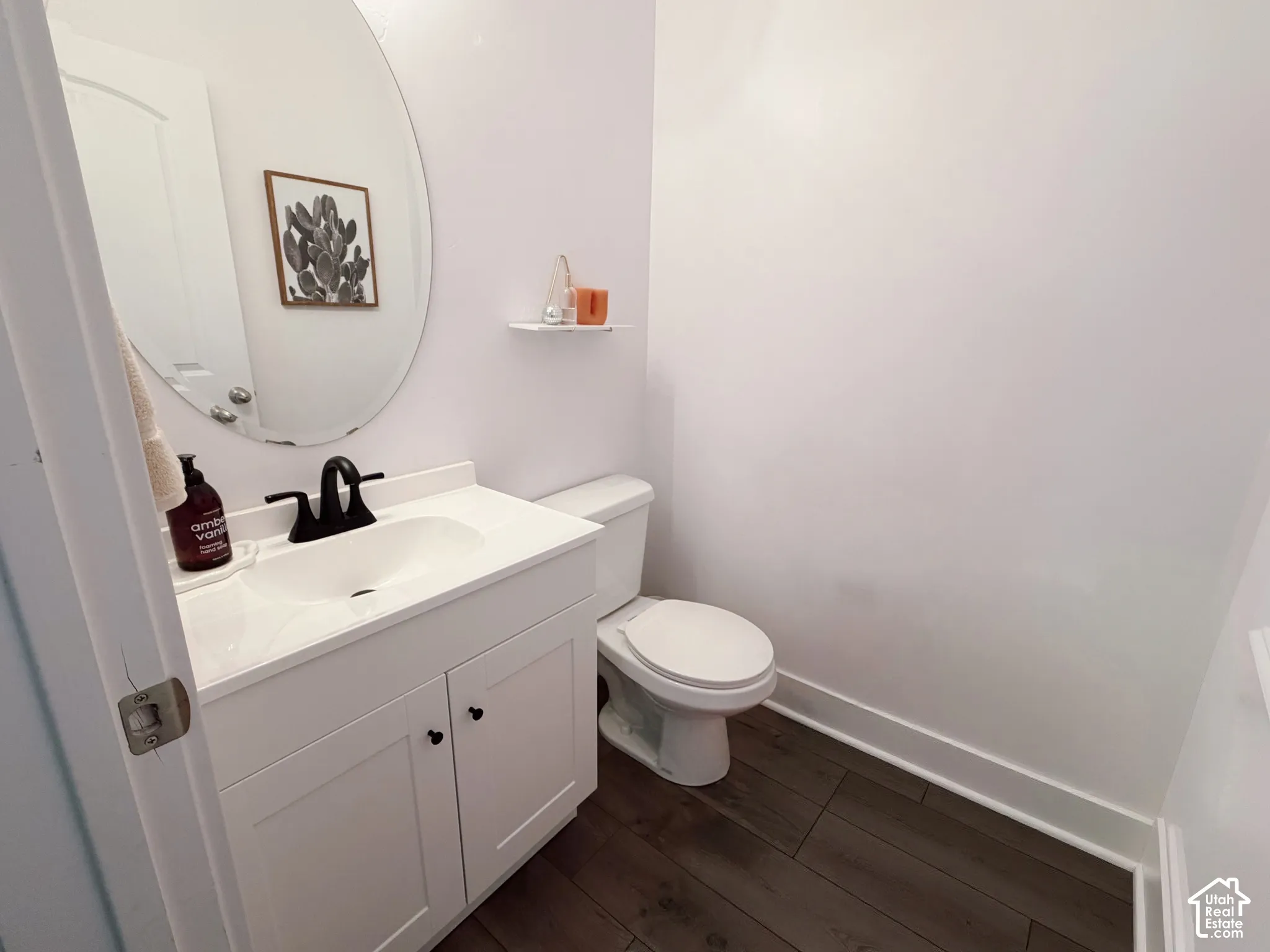 White vanity with shaker-style cabinetry, matte black faucet, and oval mirror