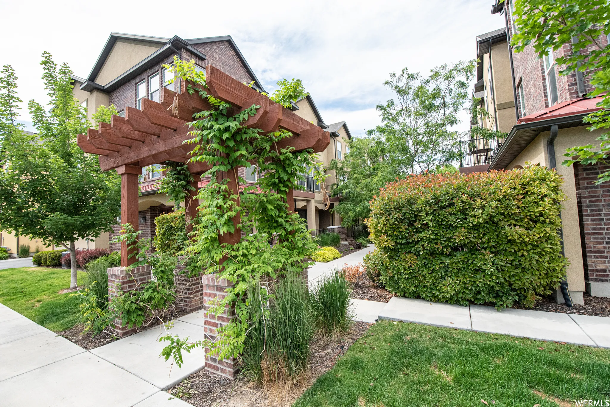 Walkway from parking lot - Wooden pergola with climbing foliage over brick pillars