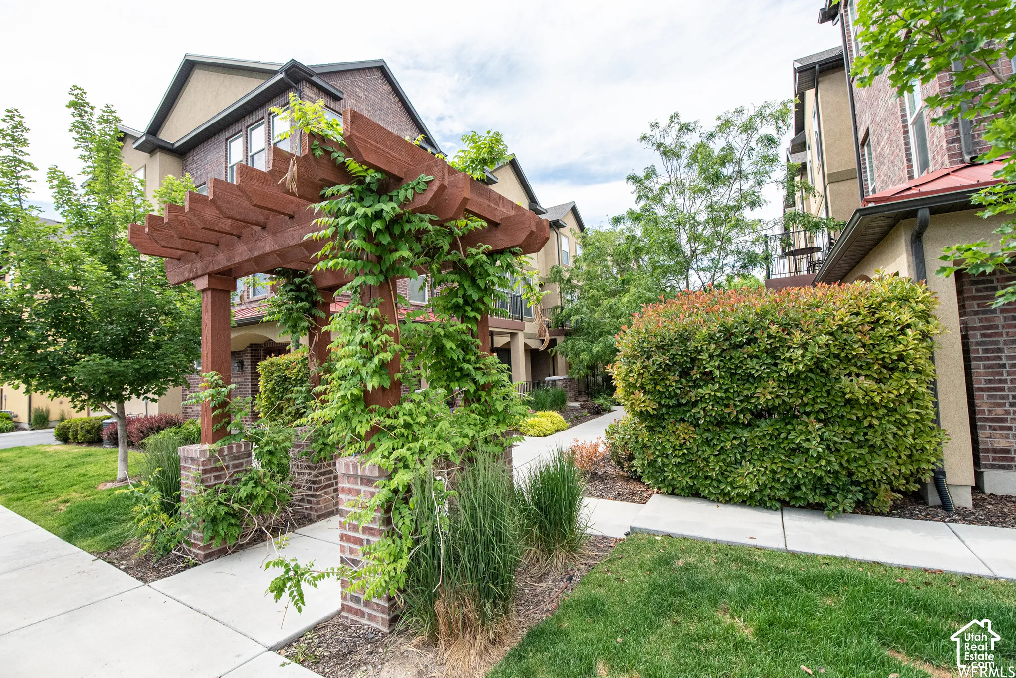Walkway from parking lot - Wooden pergola with climbing foliage over brick pillars