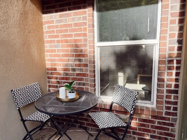 Outdoor patio space featuring a textured stucco wall and a brick exterior