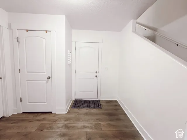 Wood-finish flooring, white walls, white doors with paneling, and a staircase with a white handrail
