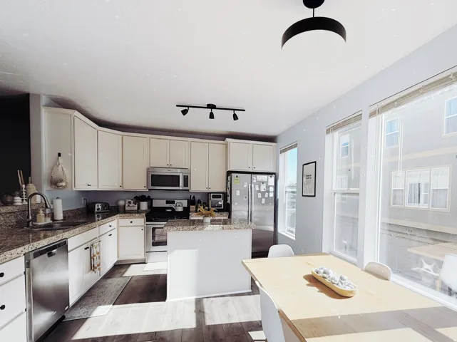 Kitchen featuring light cabinetry, granite countertops, stainless steel appliances, and wood-finish flooring