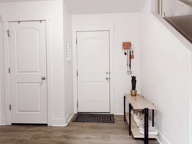 Garage doorway featuring wood-finish flooring, white paneled doors, and clean white baseboards