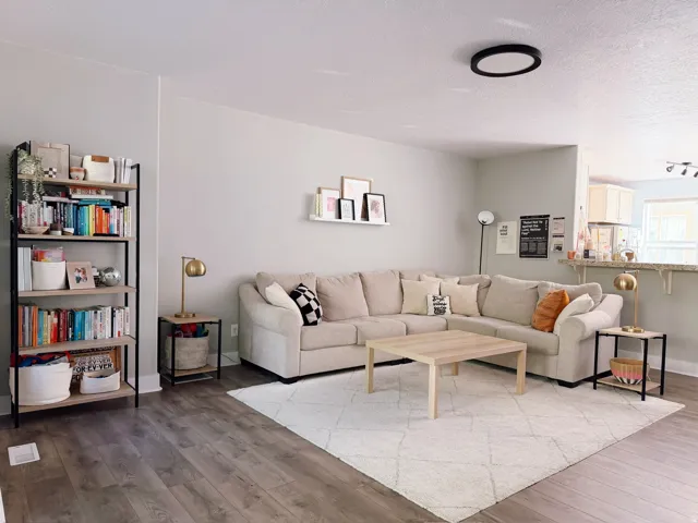 Lot's of natural light! Open-concept living area with wood-finish flooring, a neutral color palette, and an integrated breakfast bar