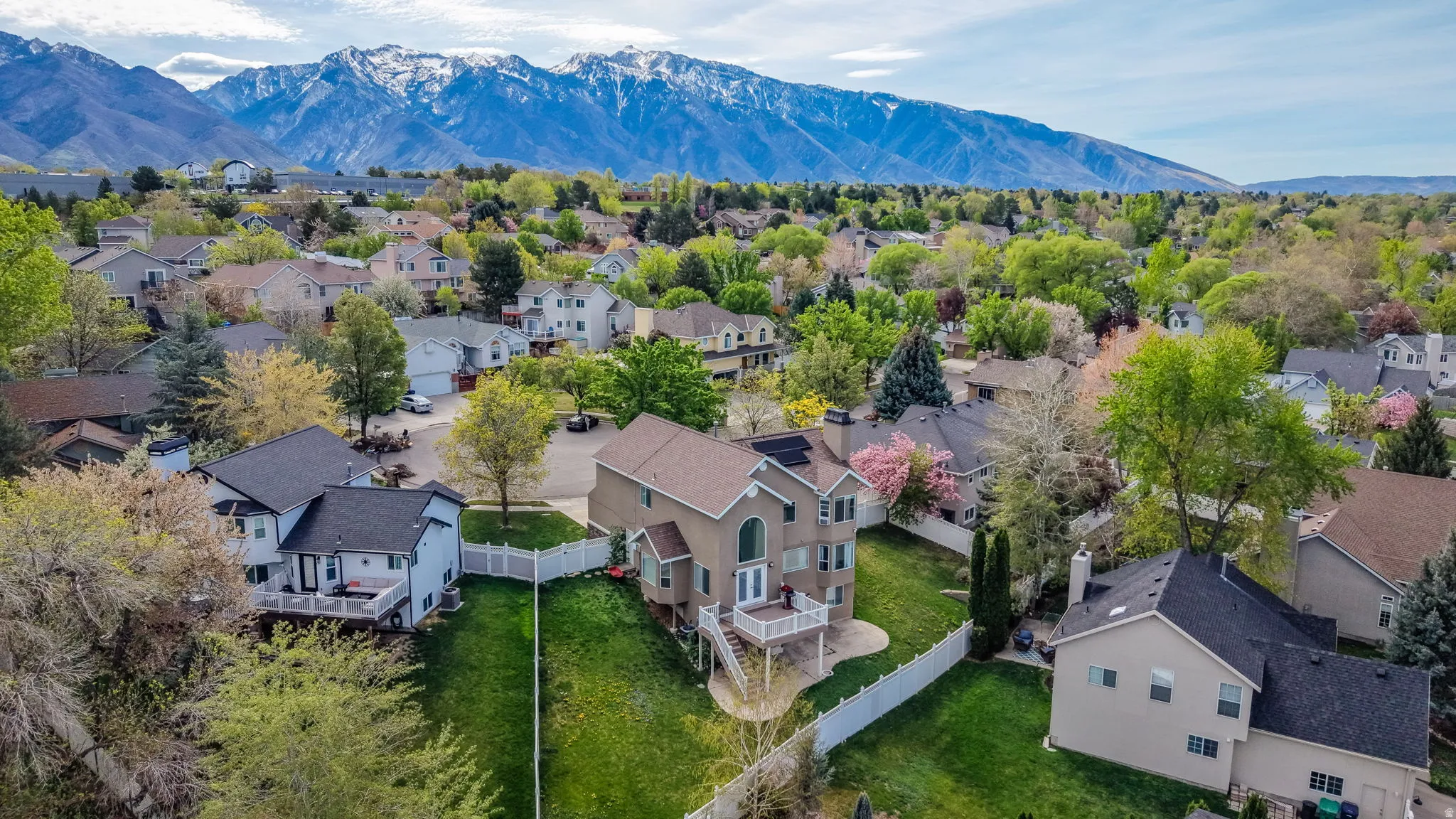 Two-story residence featuring a walk-out lower level, upper-level deck, and mature landscaping