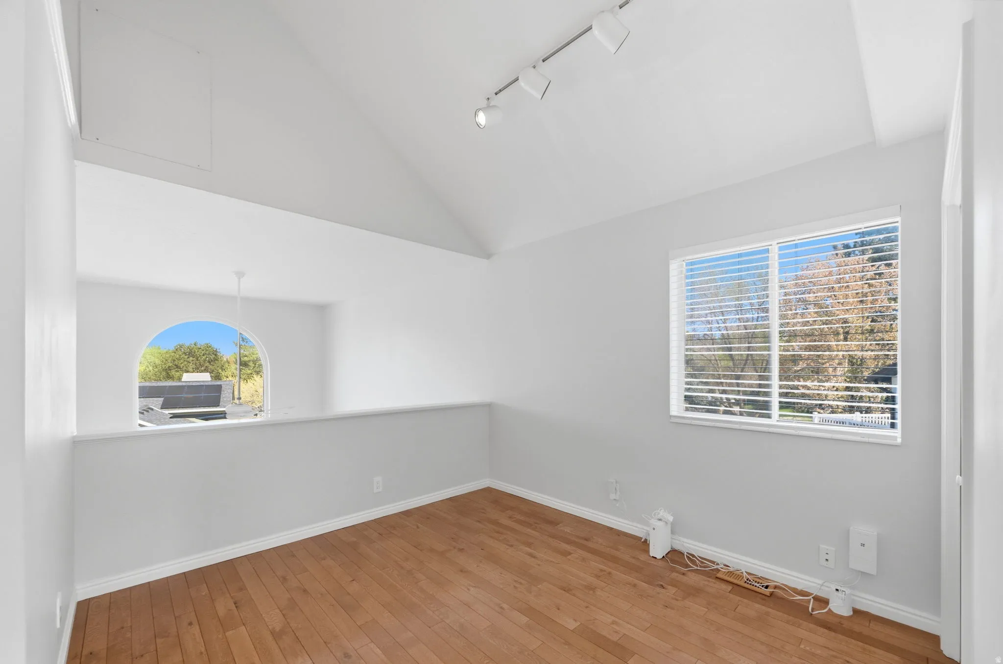 Bright room featuring wood-finish flooring and a vaulted ceiling