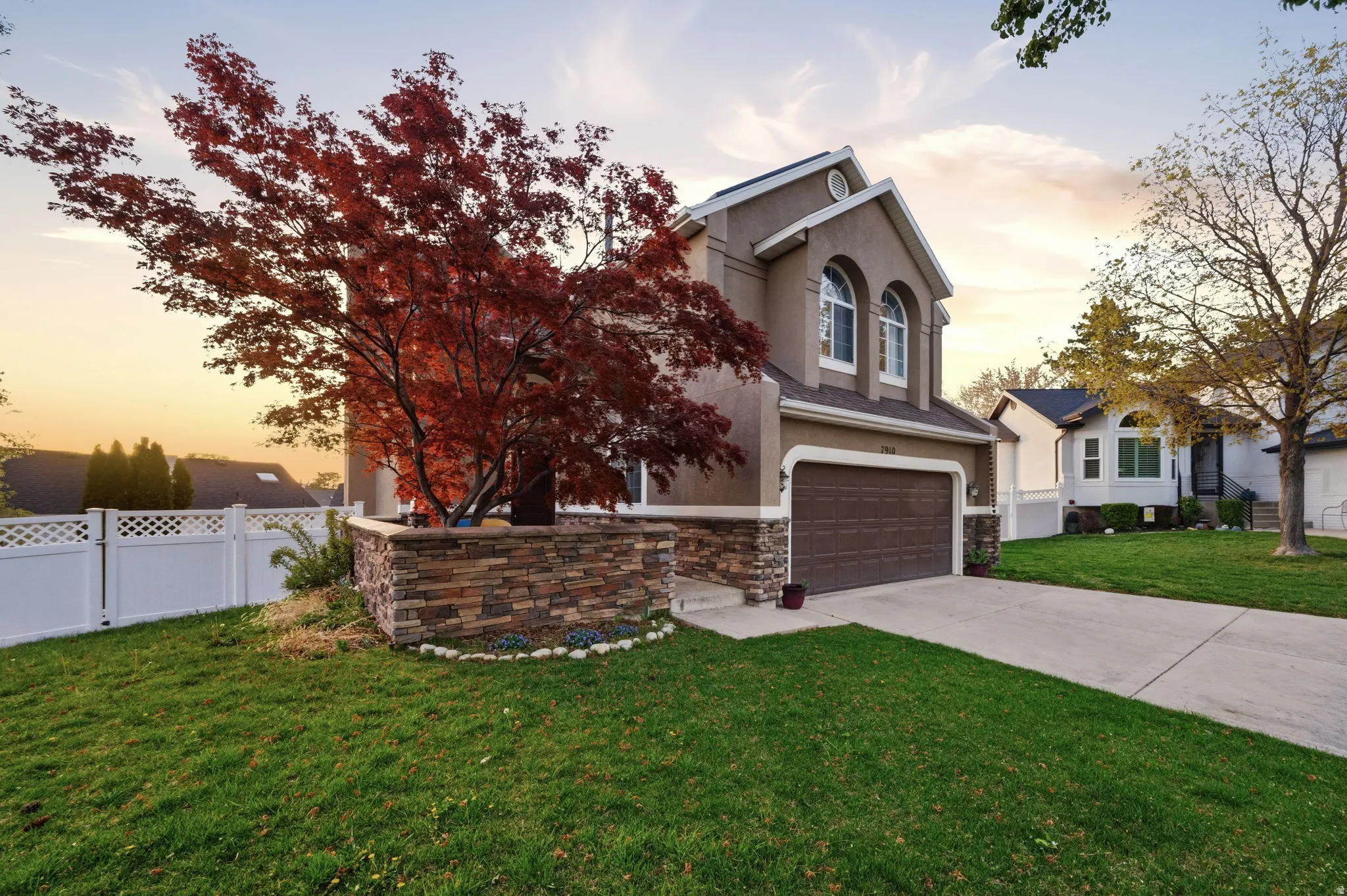 Stucco exterior featuring a prominent red-leafed tree within a stacked stone planter