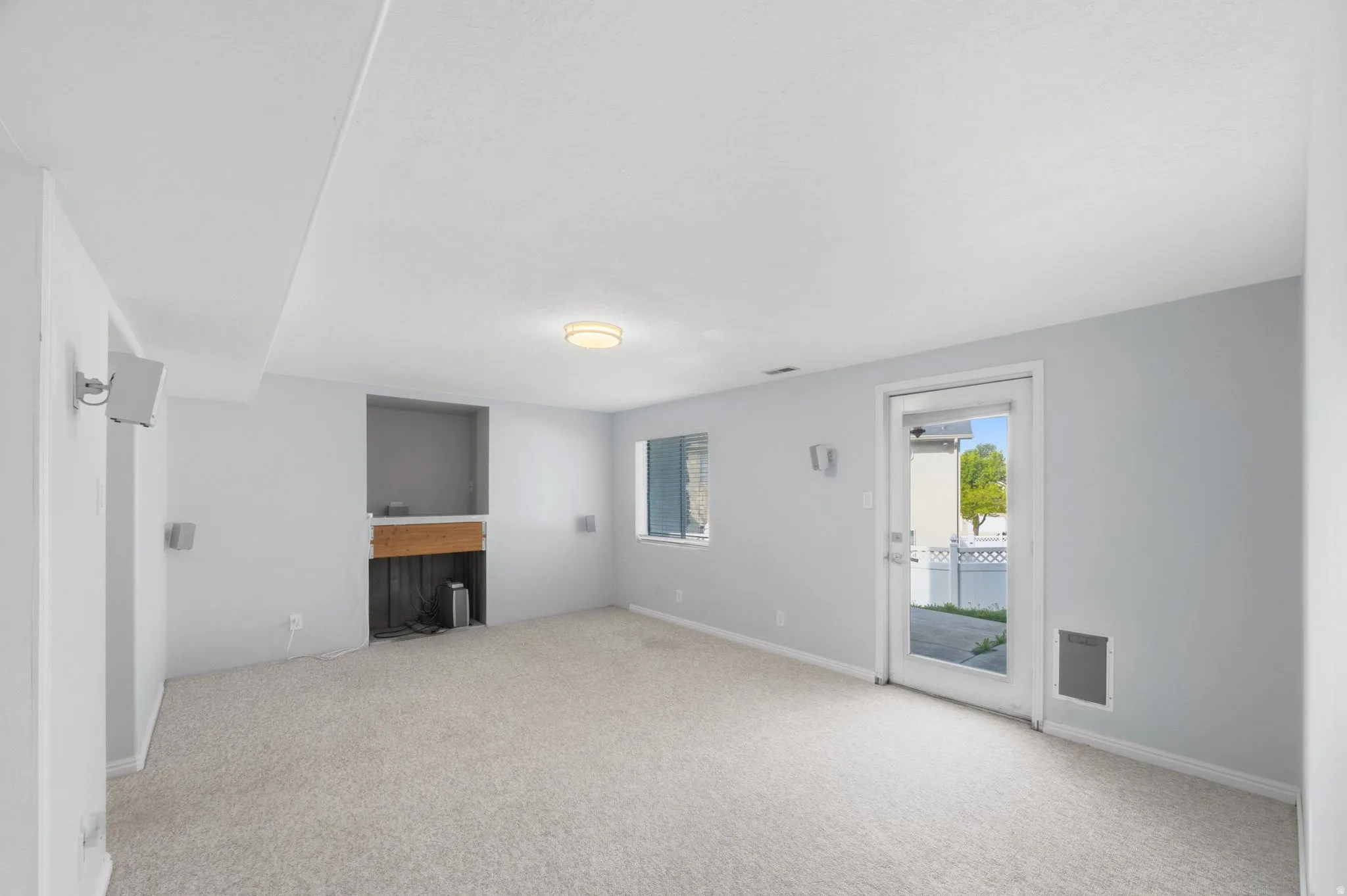 Carpeted living space featuring a fireplace niche with a wood mantel, light gray walls, and recessed lighting
