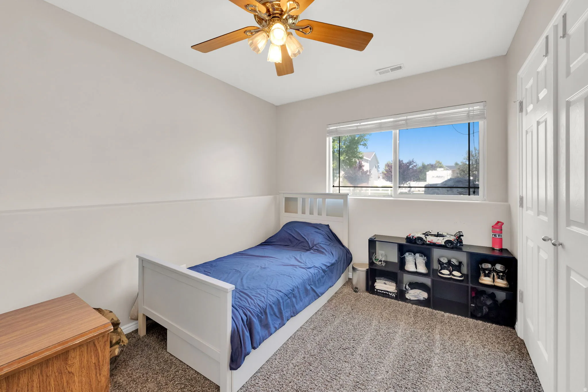 Bright room featuring a large window, neutral wall paint, and textured carpeting