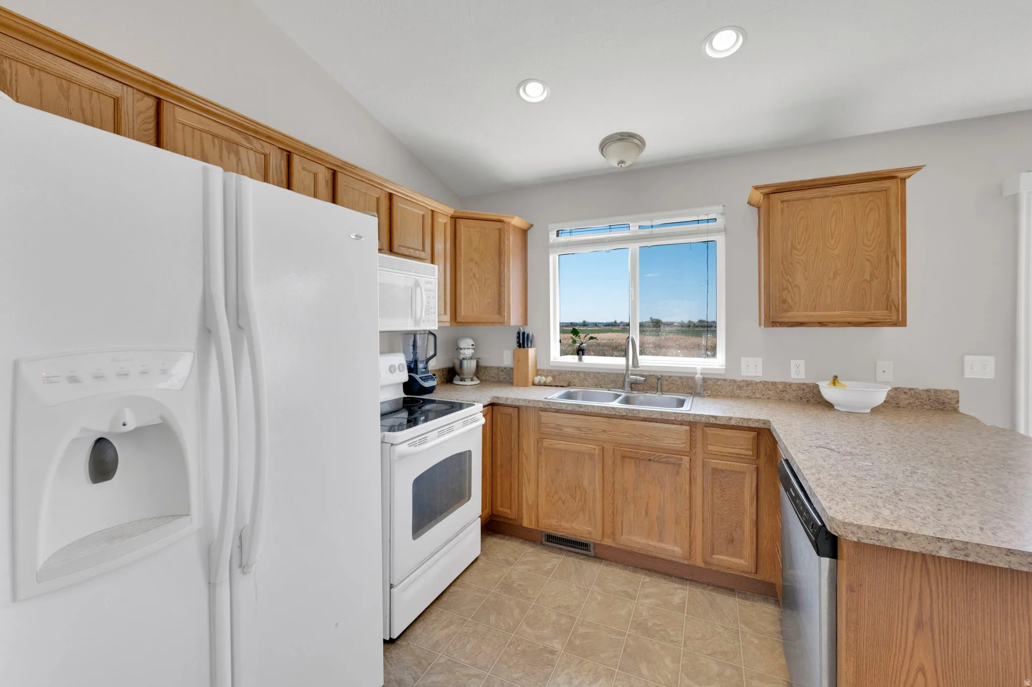 U-shaped kitchen featuring wood cabinetry, laminate countertops, a stainless steel sink with a gooseneck faucet, and recessed lighting