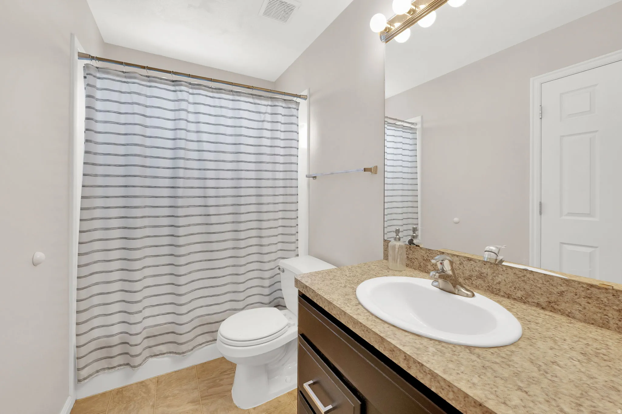 Bathroom featuring a vanity with a light-toned countertop, an integrated sink, and a multi-bulb light fixture