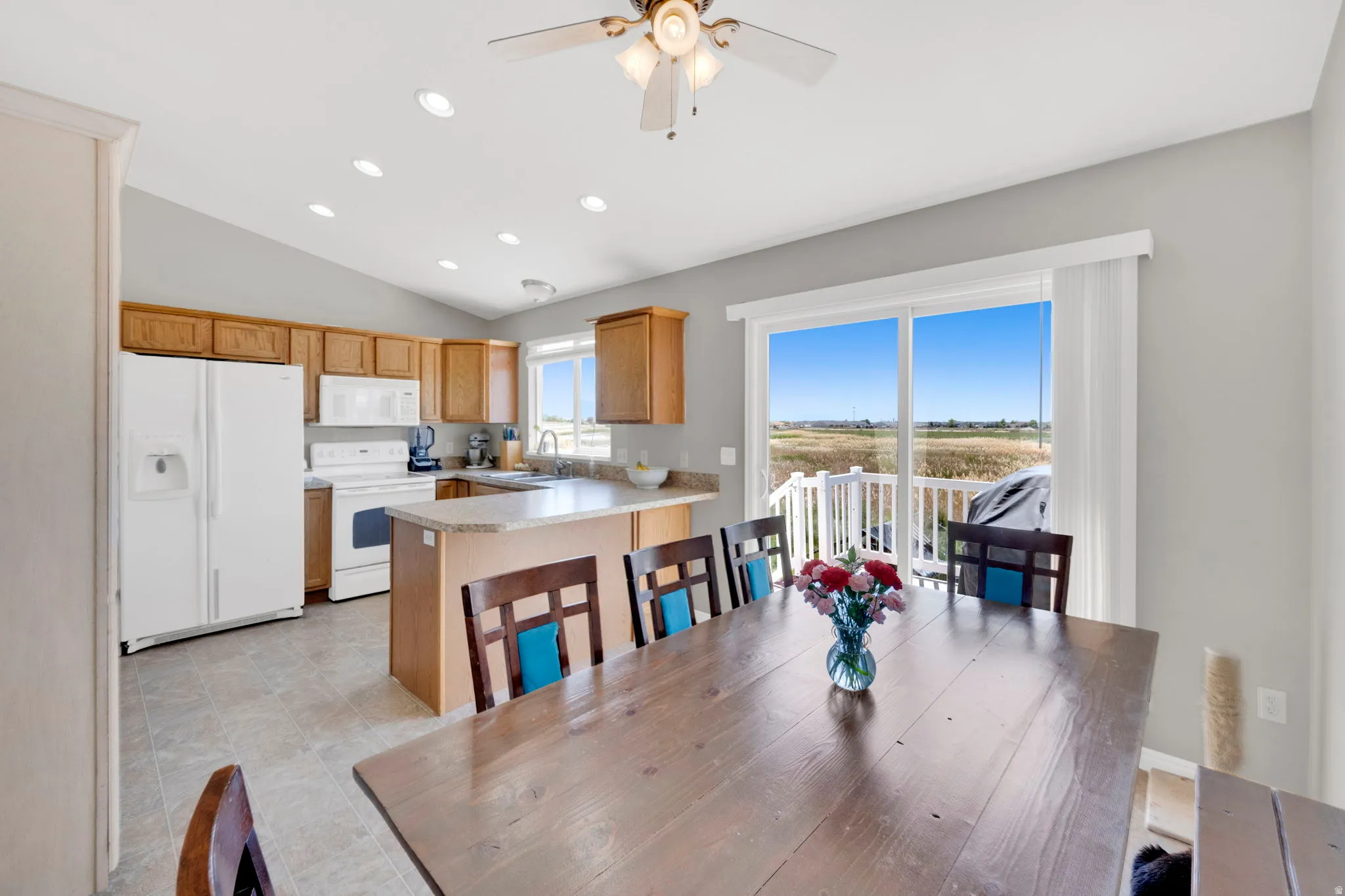 Open-concept kitchen and dining area featuring a vaulted ceiling with recessed lighting and a ceiling fan