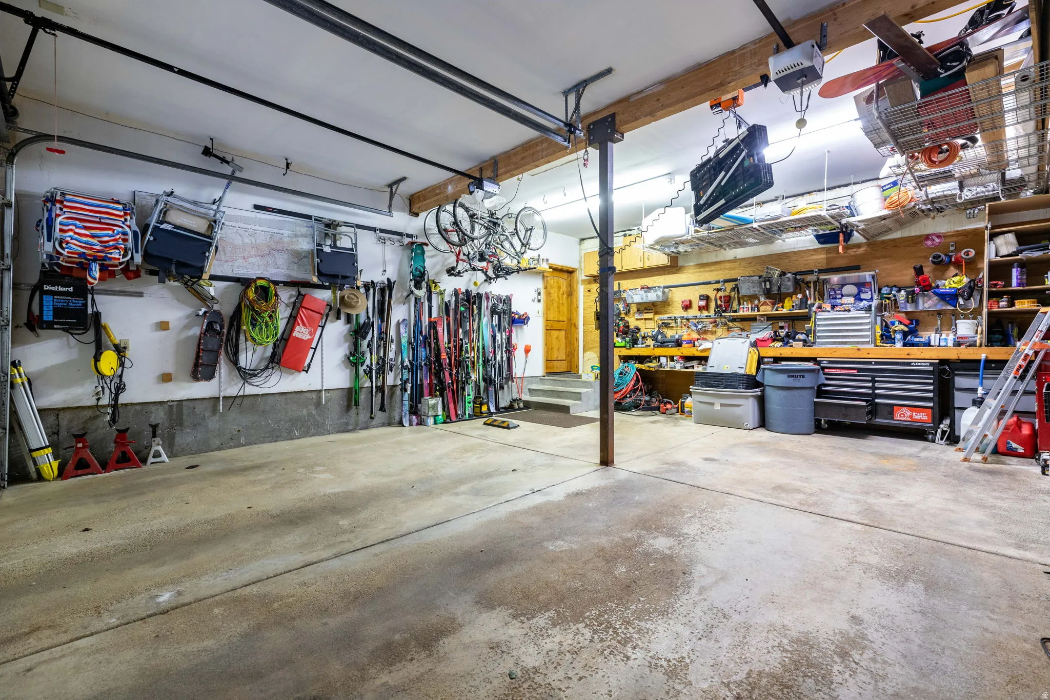 Spacious garage featuring concrete flooring, exposed wood beams, and an integrated workbench