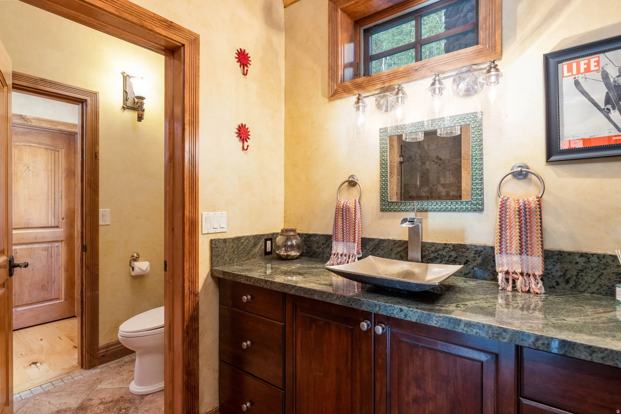 Powder room featuring a dark wood vanity with a solid surface countertop, vessel sink, and wall-mounted light fixture