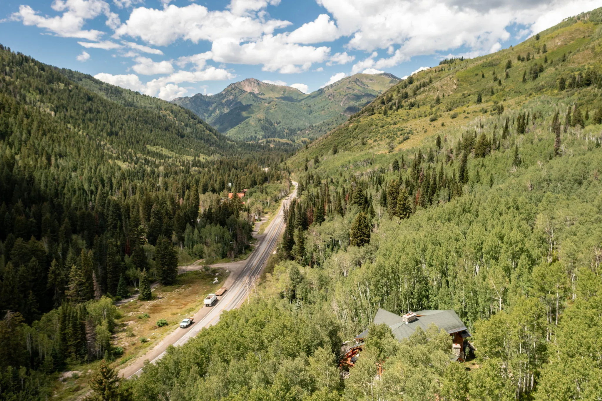 Property situated within a verdant valley, surrounded by extensive tree coverage and distant mountains