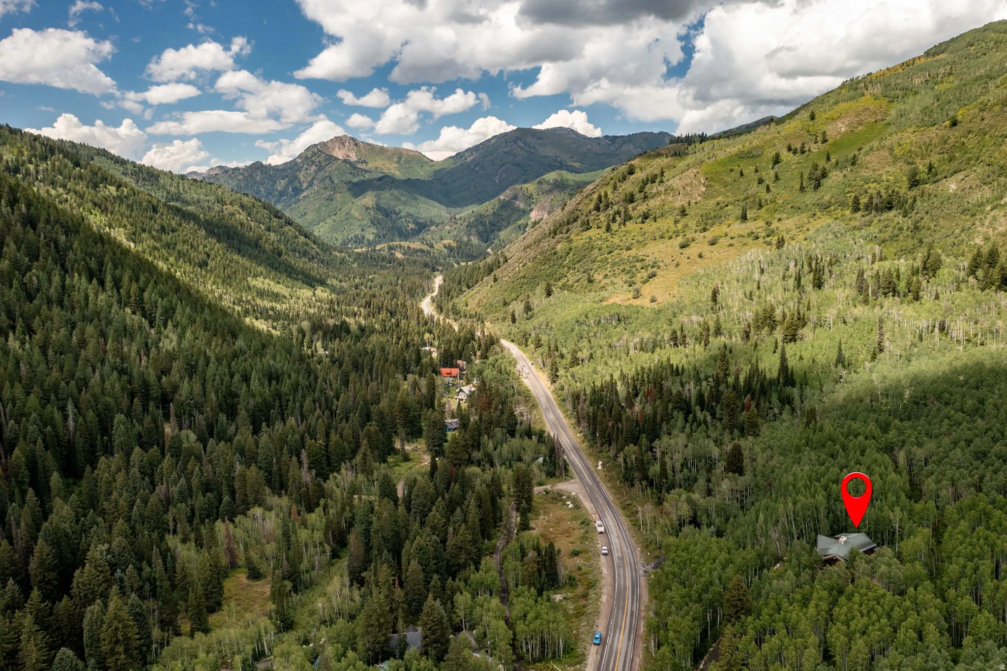 Mountain valley setting with extensive tree coverage and a paved road