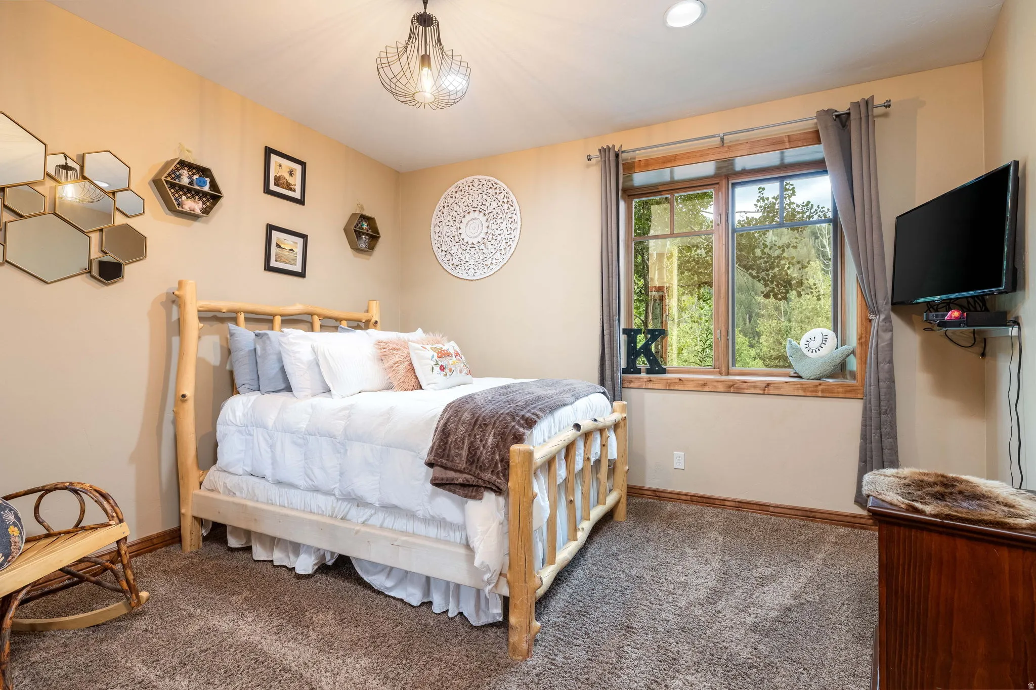 Carpeted room featuring a large window with wood trim, a built-in wall-mounted television bracket, and a ceiling-mounted light fixture