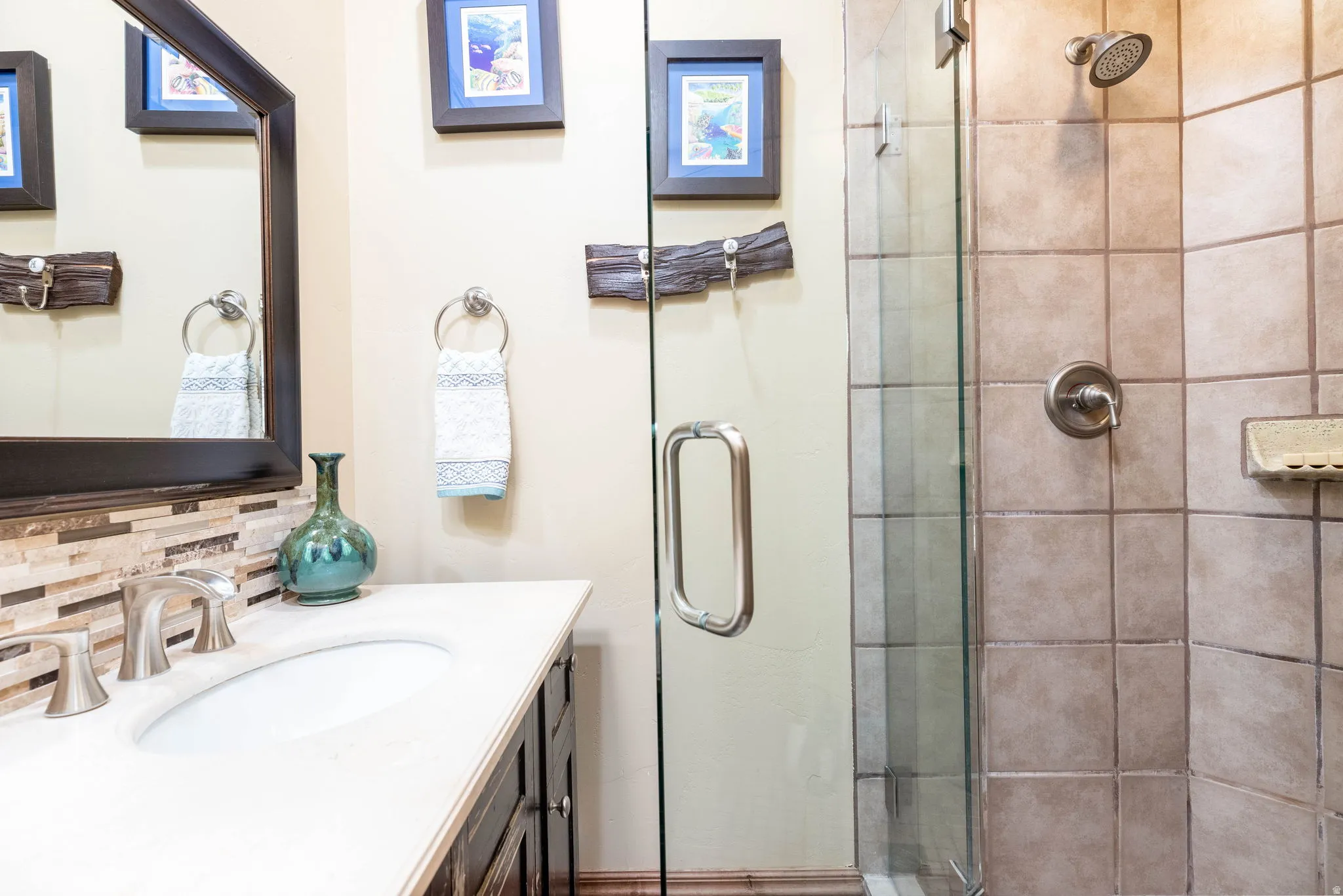Bathroom featuring a vanity with an undermount sink, brushed nickel faucet, and a tiled backsplash