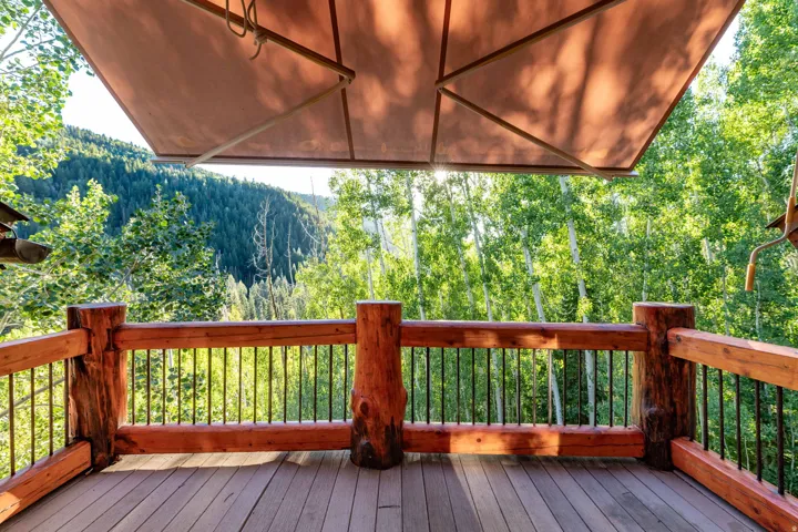 Expansive outdoor deck featuring wood flooring and a rustic log railing system
