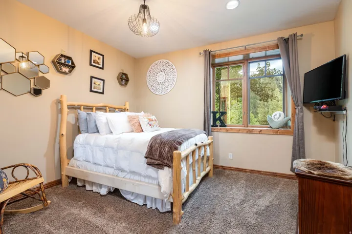 Carpeted room featuring a large window with wood trim, a built-in wall-mounted television bracket, and a ceiling-mounted light fixture