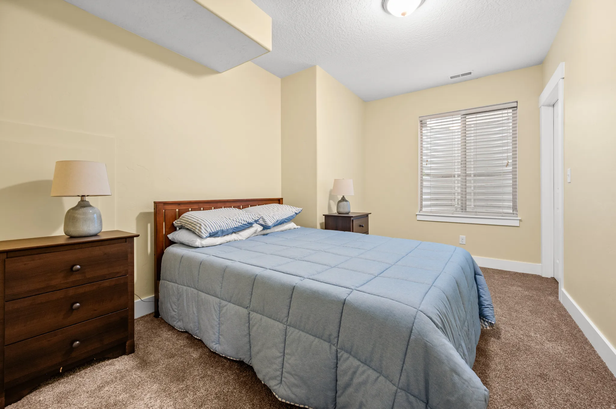 Bedroom 3 featuring neutral wall tones, textured ceiling, a window with blinds, and brown carpet flooring
