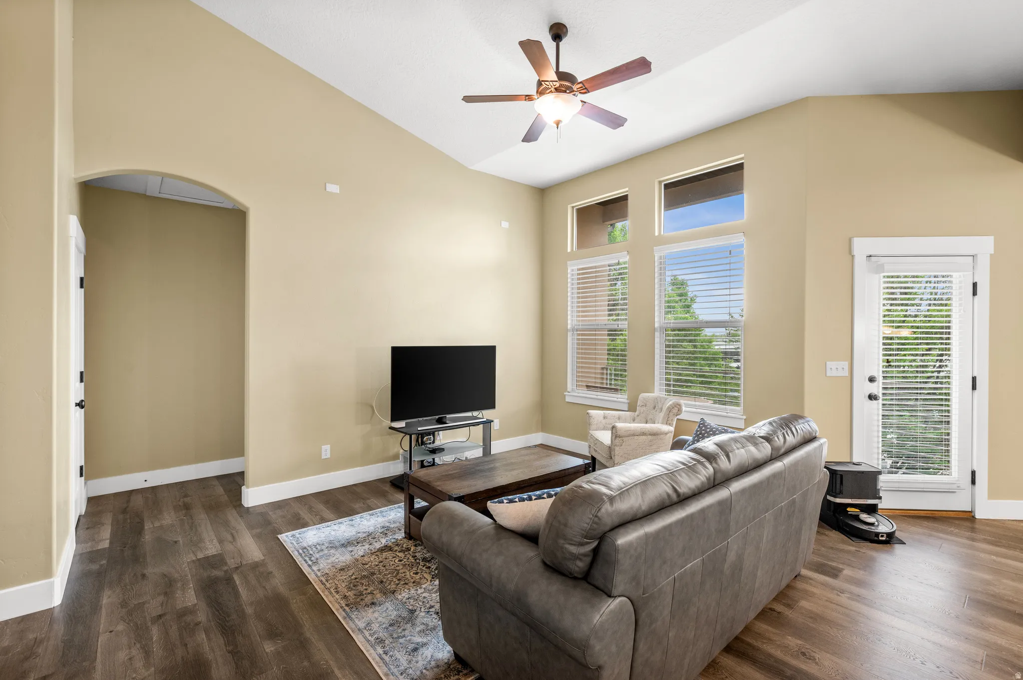 Spacious room featuring vaulted ceilings, wood-finish flooring, and multiple windows