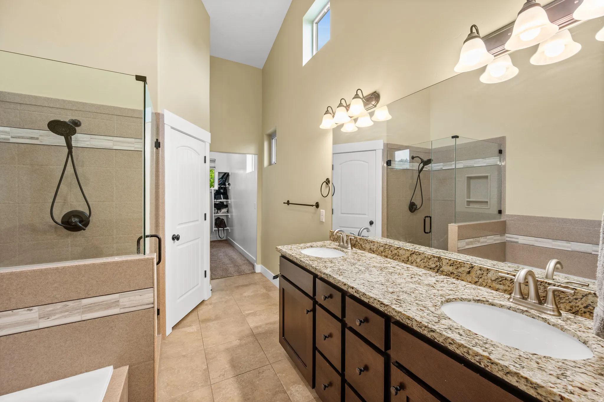 Newly renovated master bathroom featuring a double vanity with granite countertops, wood-finish cabinetry, and brushed nickel fixtures