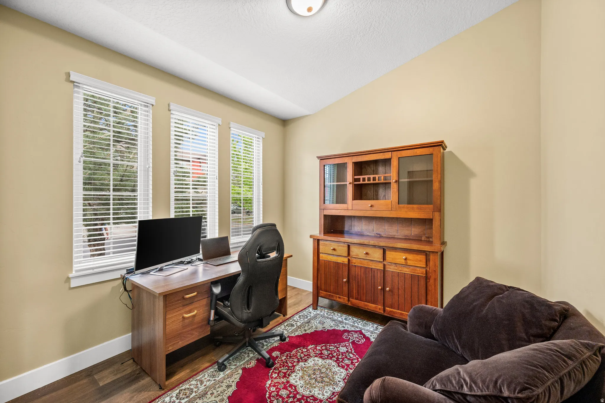Office right off the entrance  featuring three windows with blinds, wood-finish flooring, and neutral wall tones
