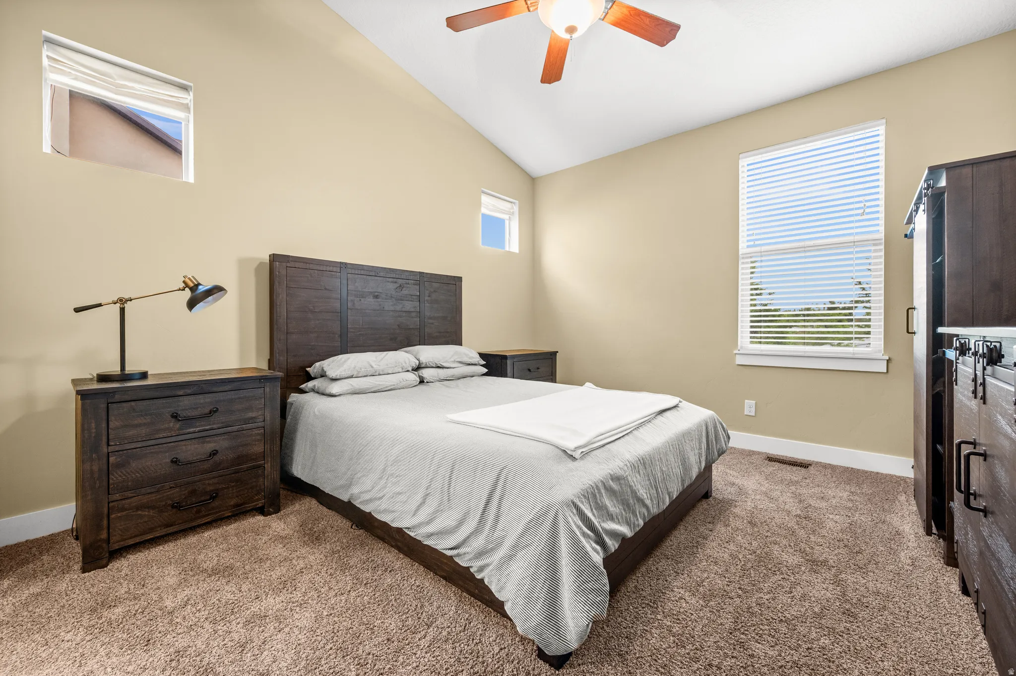 Master bedroom featuring a ceiling fan with integrated lighting, two windows with blinds, and plush carpeting