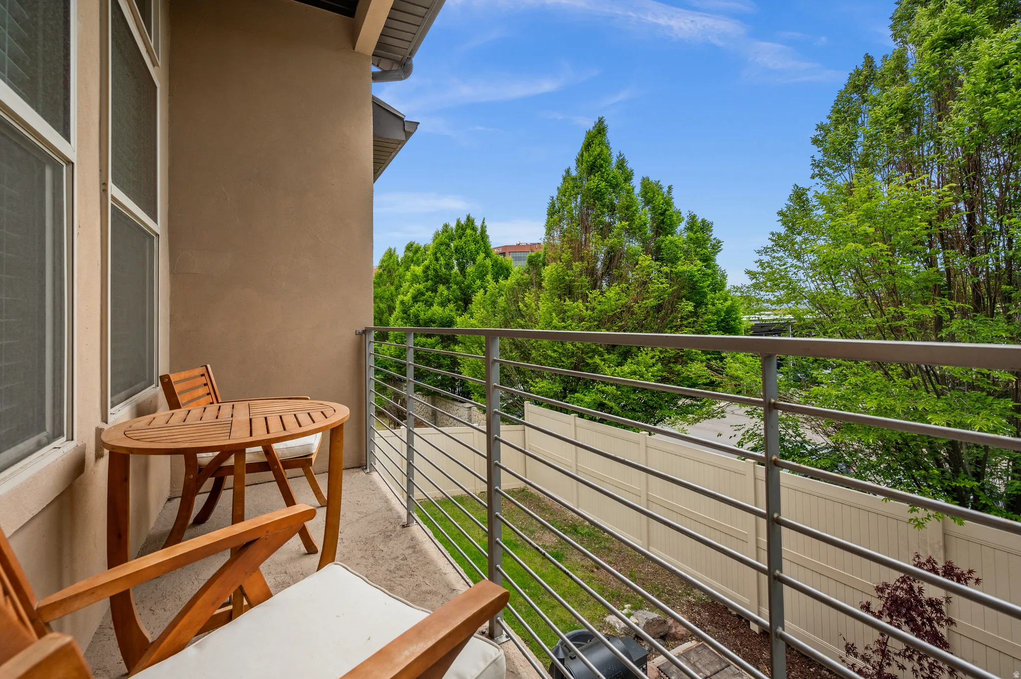 Private balcony off of the dining area featuring a stucco exterior, horizontal metal railings, and a concrete surface