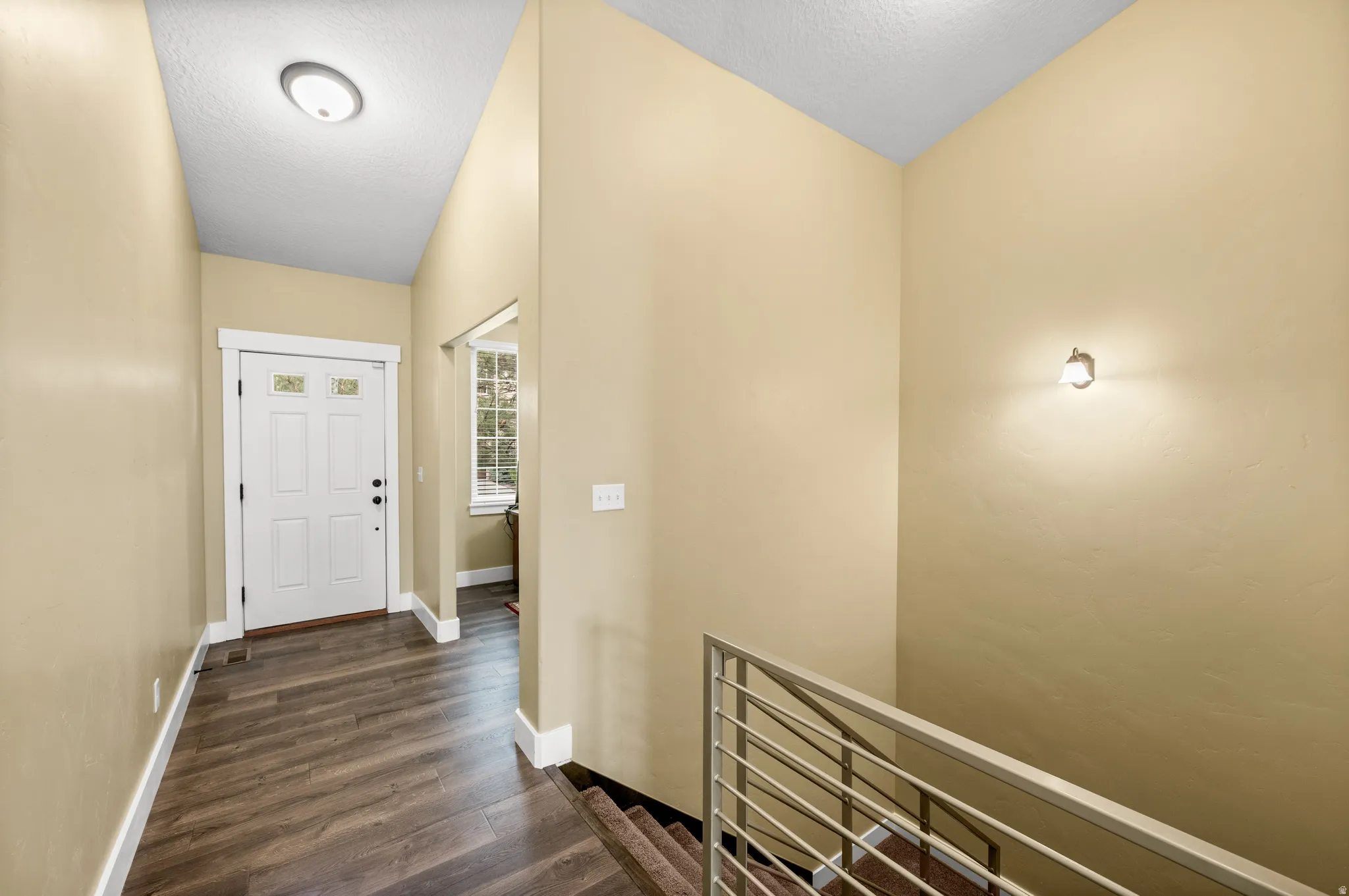 Entryway with wood-finish flooring, white trim, and a white front door featuring decorative glass inserts - wide stairway leading to basement