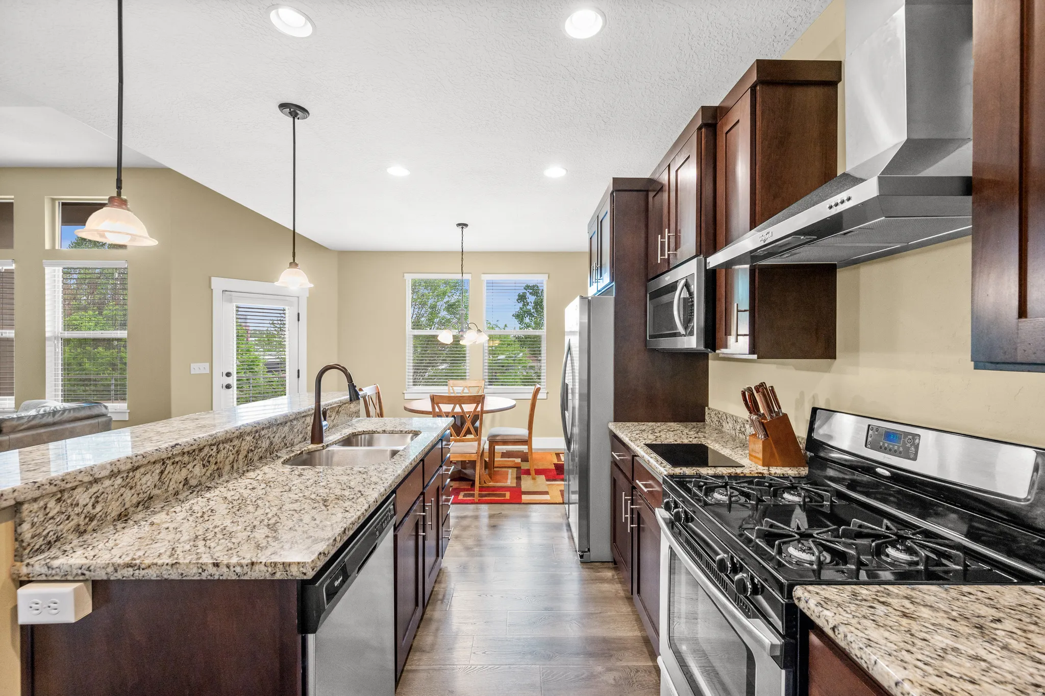 Kitchen featuring dark wood cabinetry, stainless steel appliances, and light-colored granite countertops