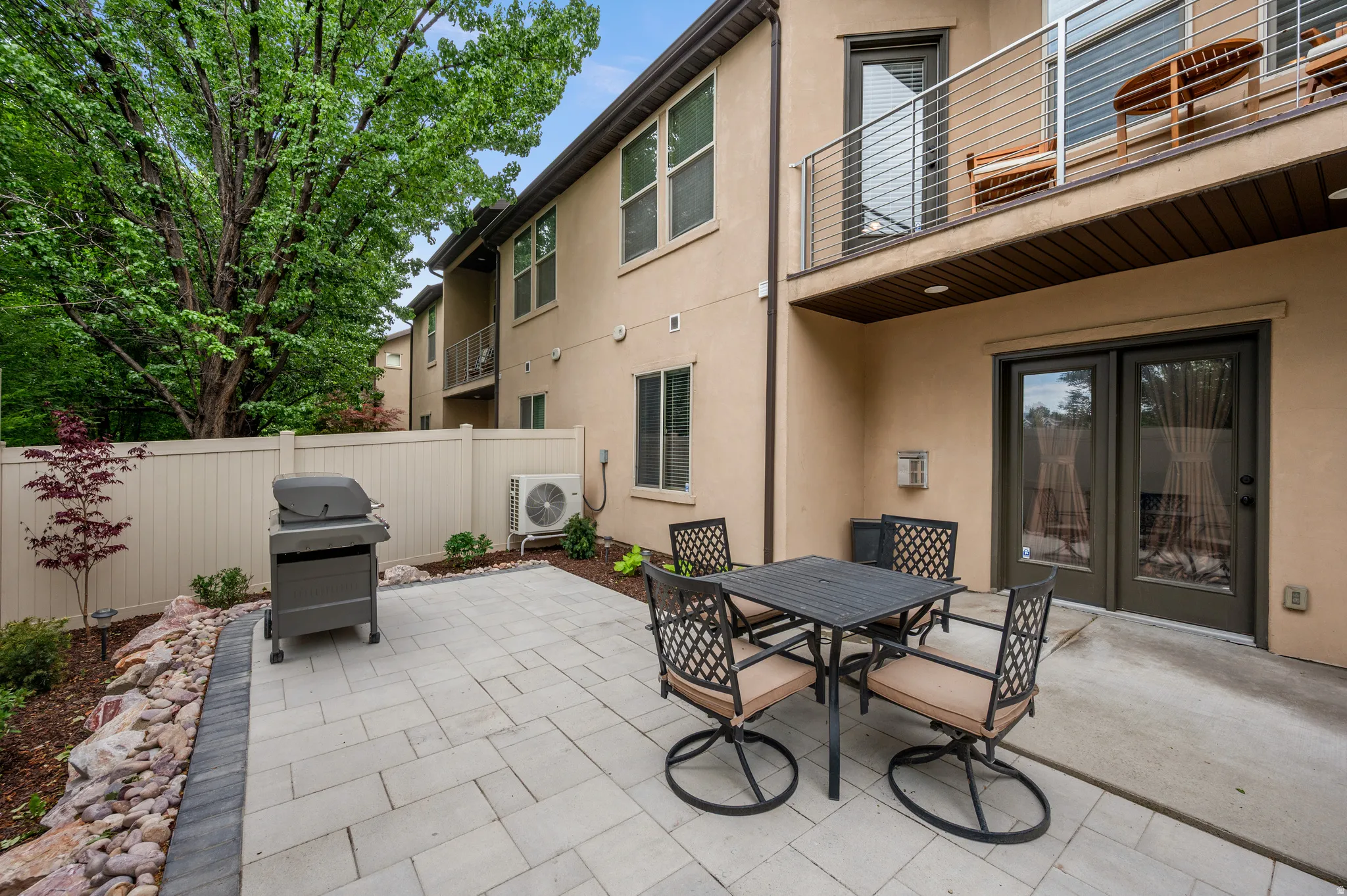 Gorgeous private patio featuring paver stones, a rock border with plantings, and a vinyl fence