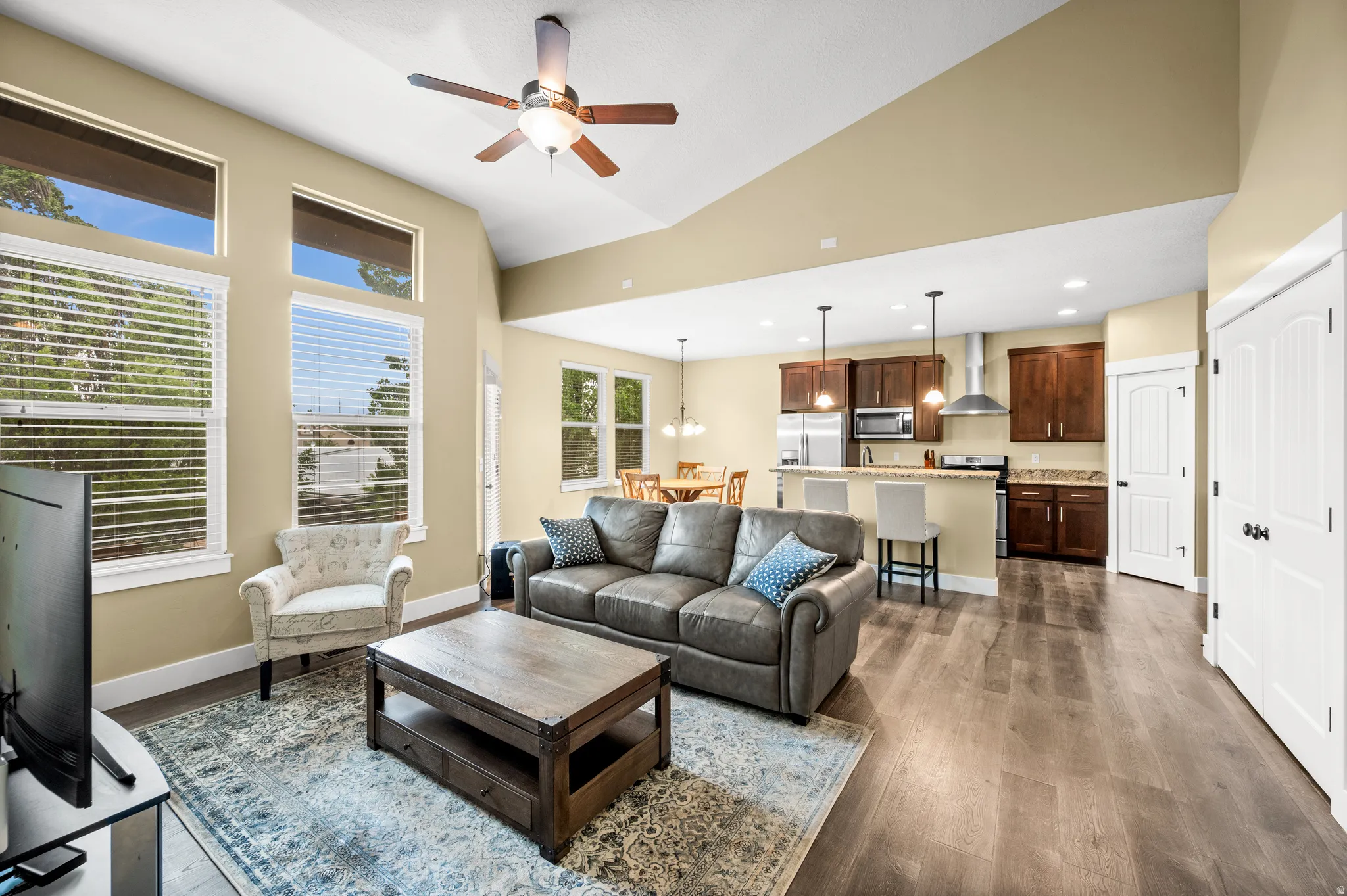 Open-concept living space featuring wood-finish flooring, vaulted ceilings, and a ceiling fan