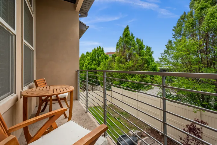 Private balcony off of the dining area featuring a stucco exterior, horizontal metal railings, and a concrete surface