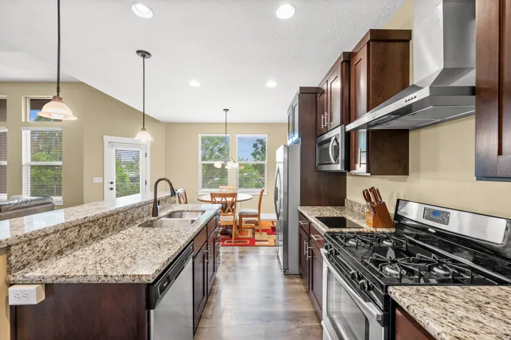 Kitchen featuring dark wood cabinetry, stainless steel appliances, and light-colored granite countertops