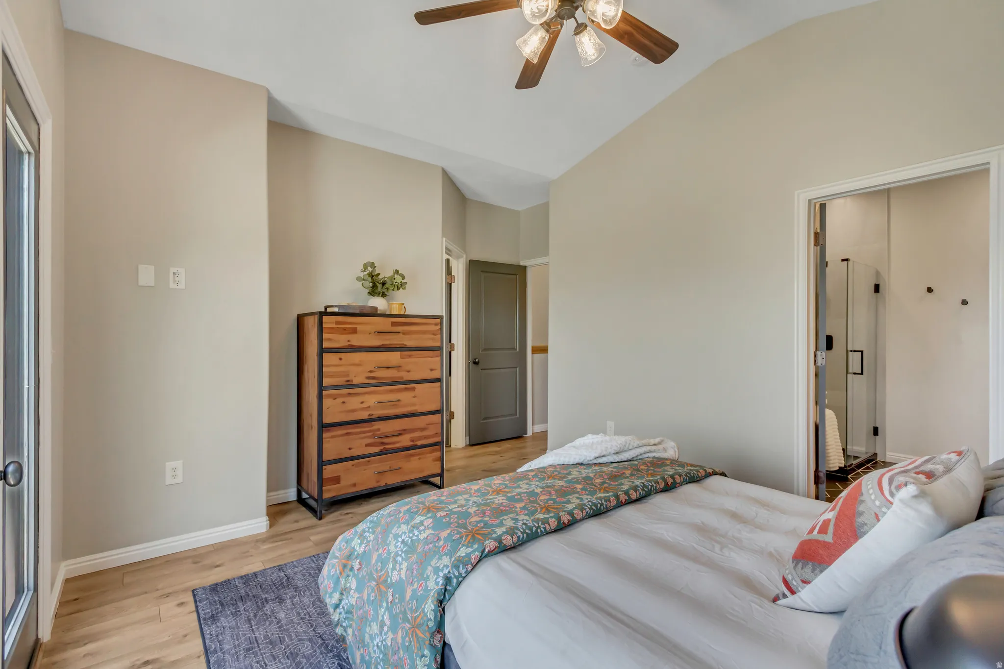 Vaulted ceiling bedroom featuring wood-finish flooring and a ceiling fan with light fixture