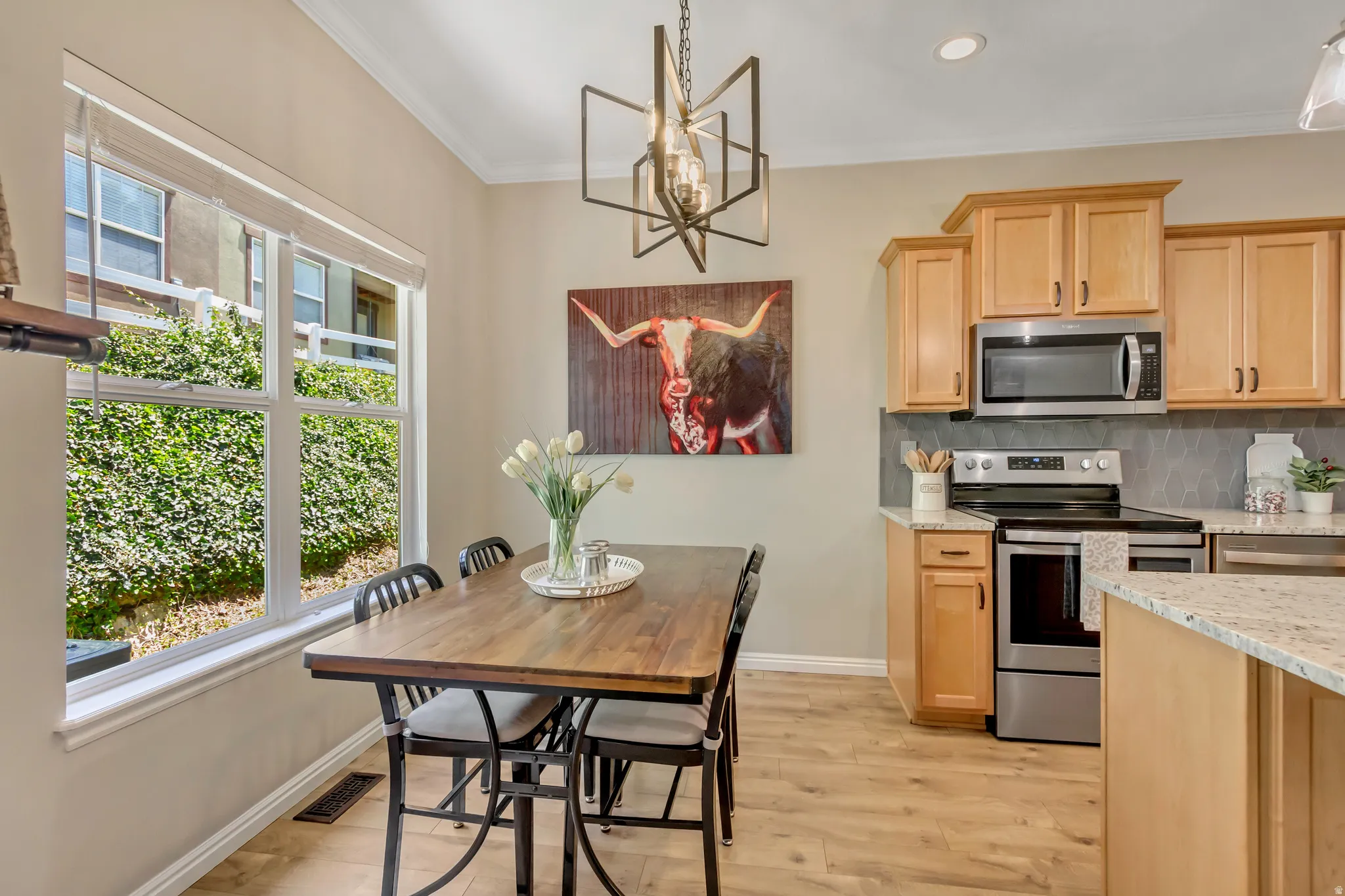 Dining area featuring a large window, wood-finish flooring, and a contemporary chandelier