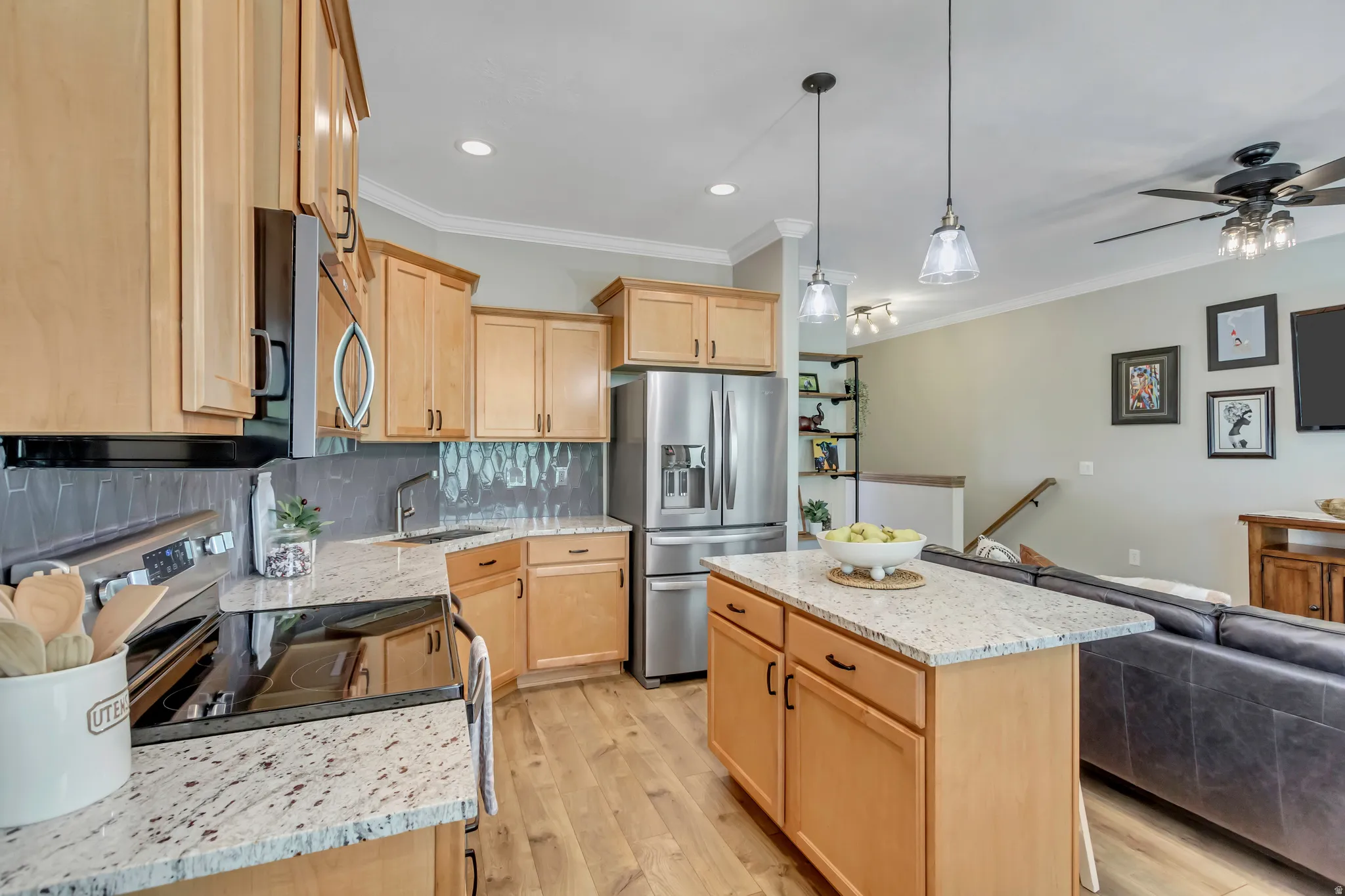 Modern kitchen featuring light wood cabinetry, tile backsplash and granite countertops