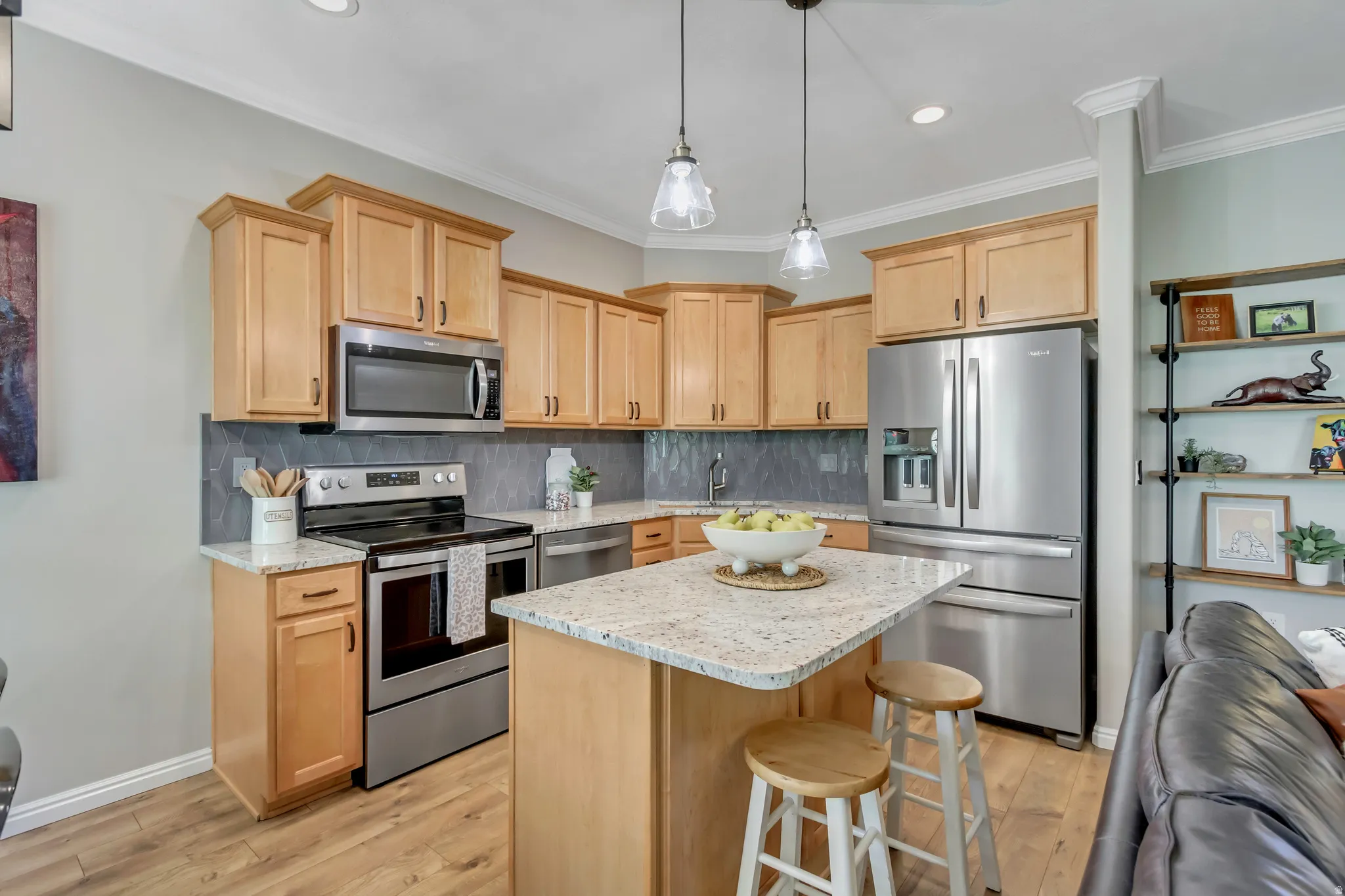 Kitchen featuring wood-finish cabinetry, stainless steel appliances, granite countertops, and a central island with pendant lighting