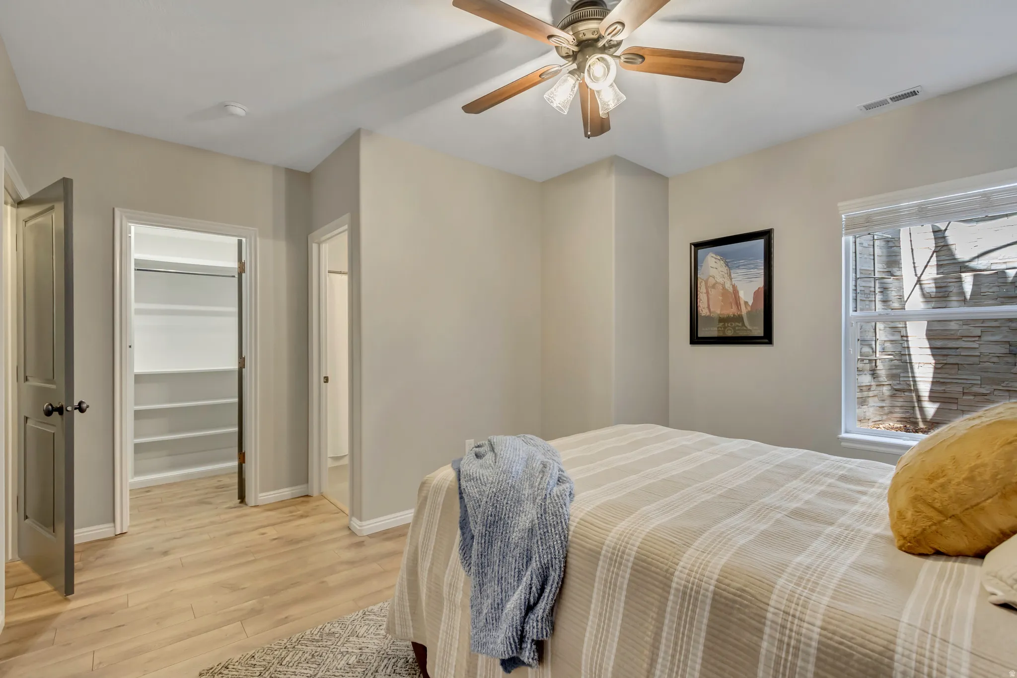 Second primary suite featuring wood-finish flooring, a ceiling fan, walk in closet and a window with blinds