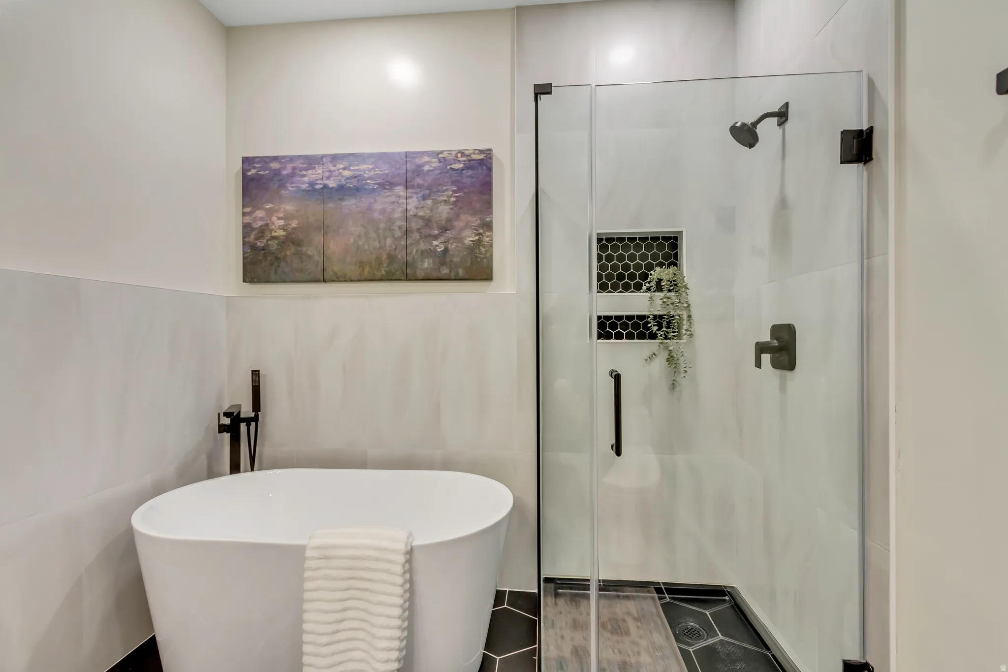 Contemporary bathroom featuring a freestanding soaking tub, a glass-enclosed shower with black hexagonal tile accents, and matte black fixtures