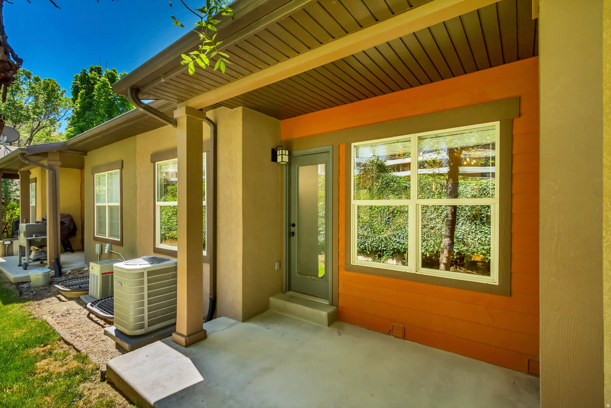 Exterior patio area featuring a concrete surface, stucco siding, and a contrasting orange accent wall