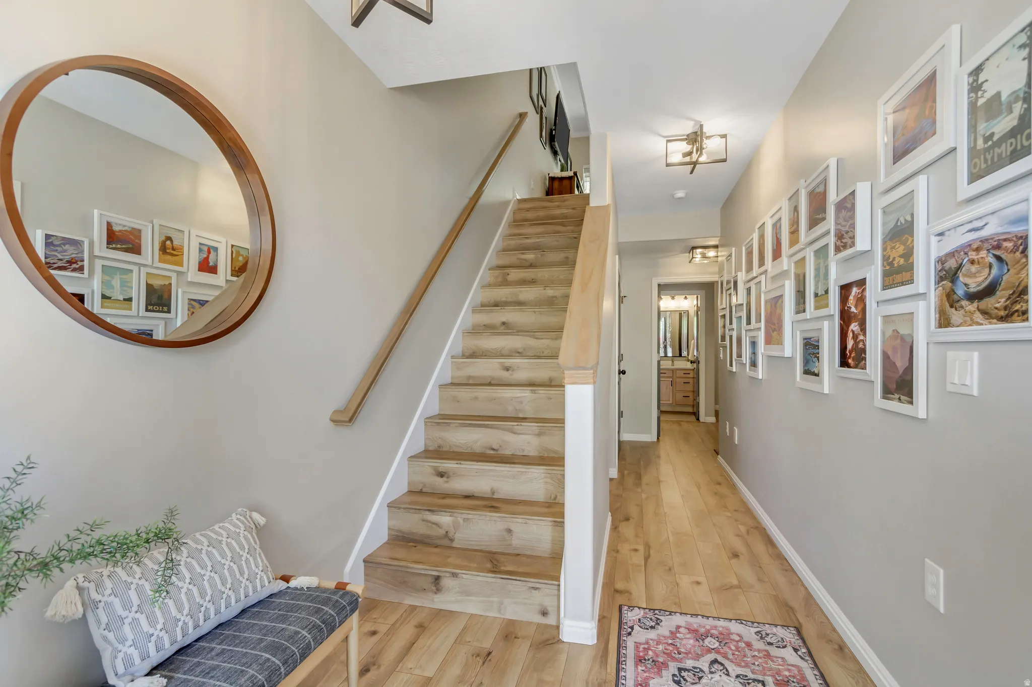 Inviting entryway featuring wood-finish flooring, a contemporary staircase with a light wood handrail, and modern overhead lighting fixtures