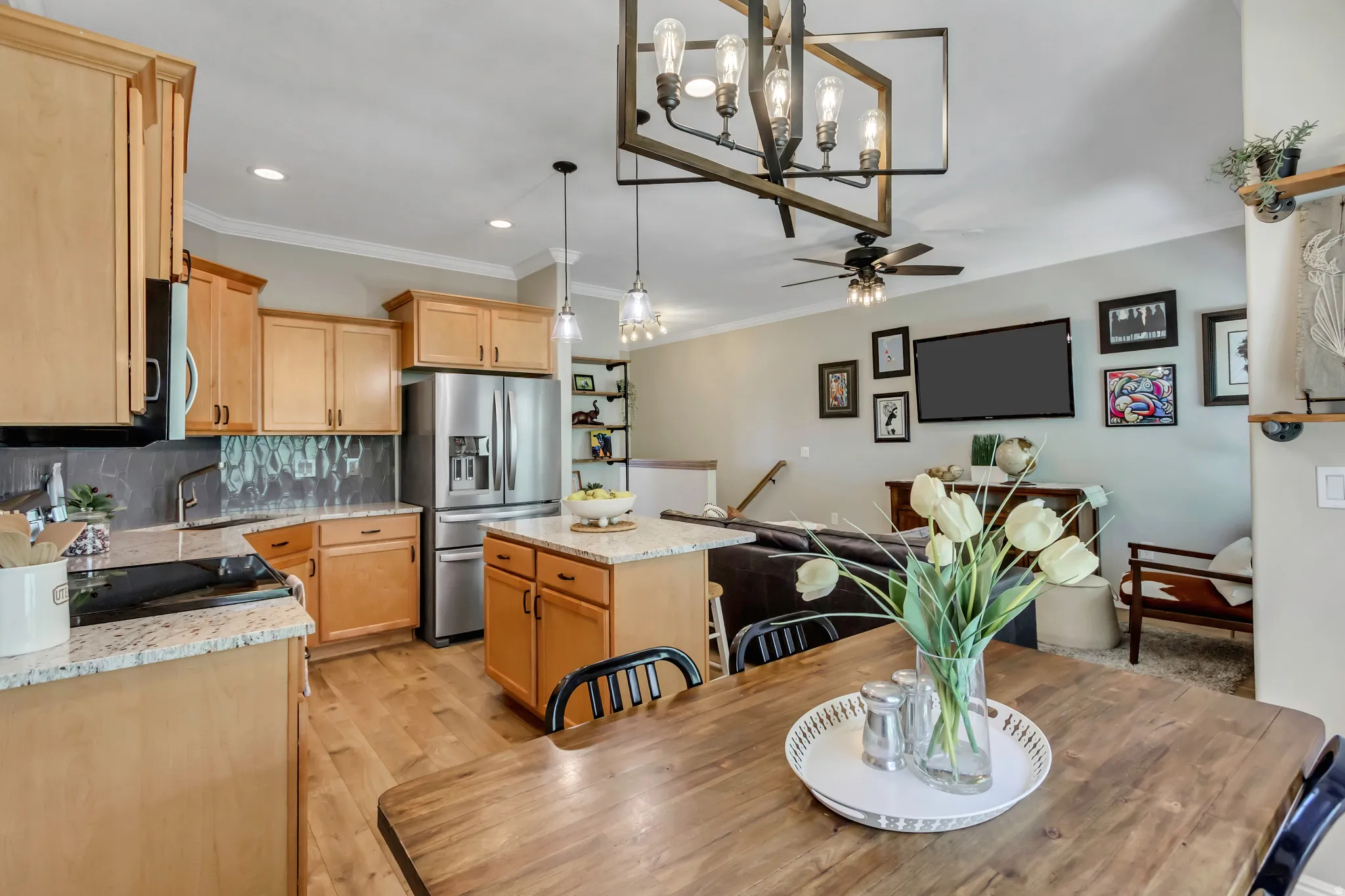 Open-concept living space featuring a kitchen with light wood cabinetry, stainless steel appliances, and granite countertops