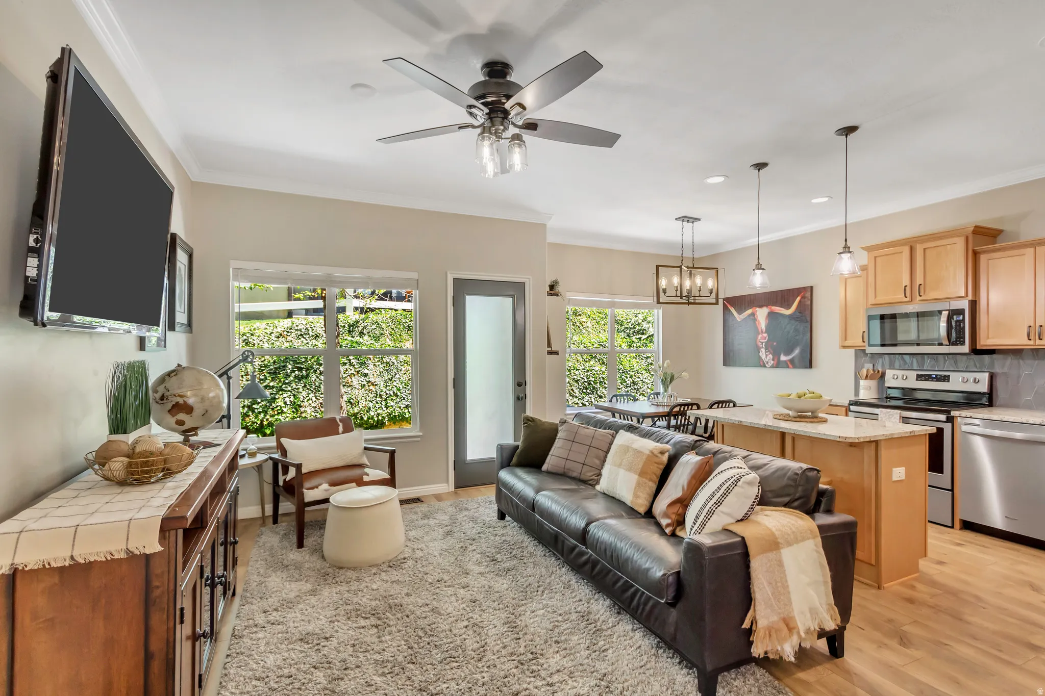 Open-concept living area featuring wood-finish flooring, a contemporary ceiling fan, recessed lighting, and crown molding