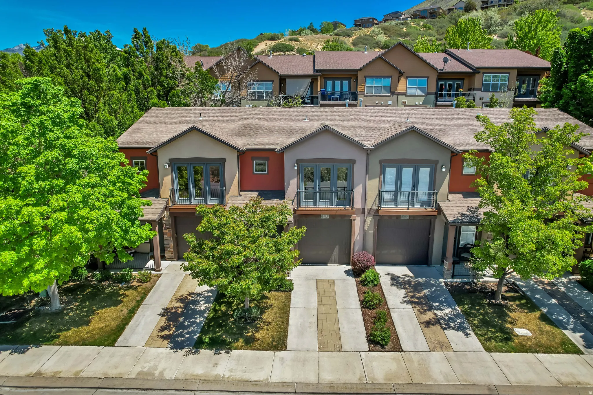 Modern multi-story townhome featuring a neutral stucco and warm-toned siding exterior
